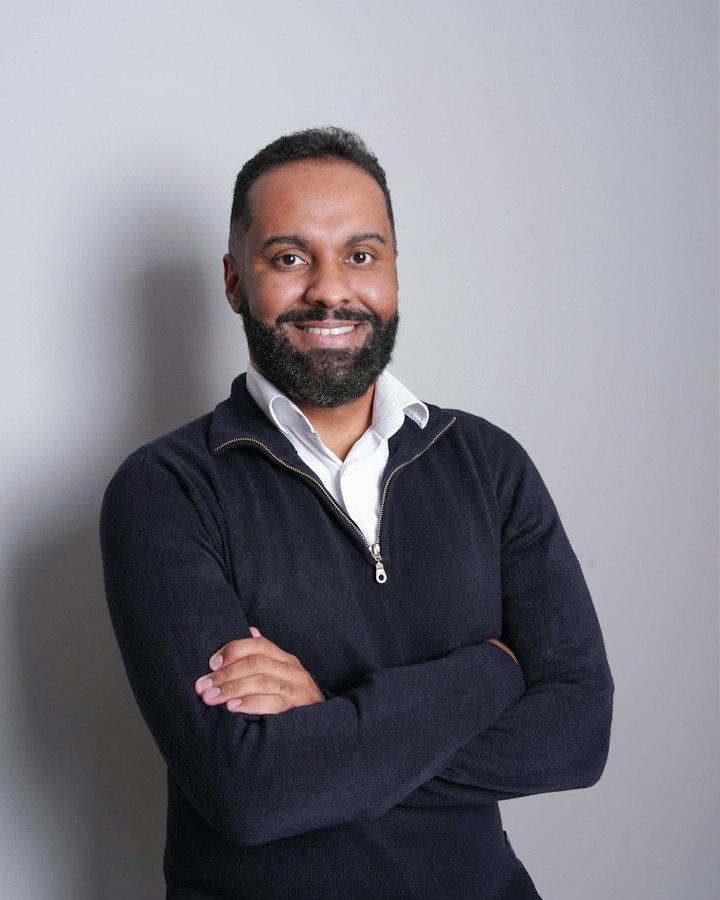 A professional in a navy sweater, arms folded, smiling