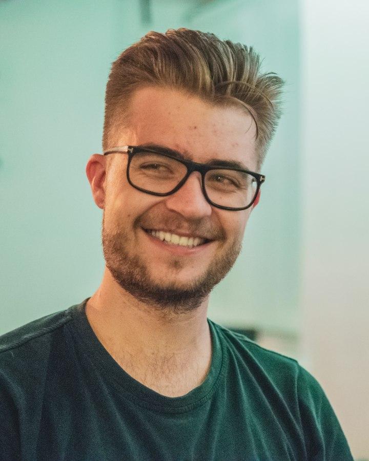 A young man in glasses, smiling