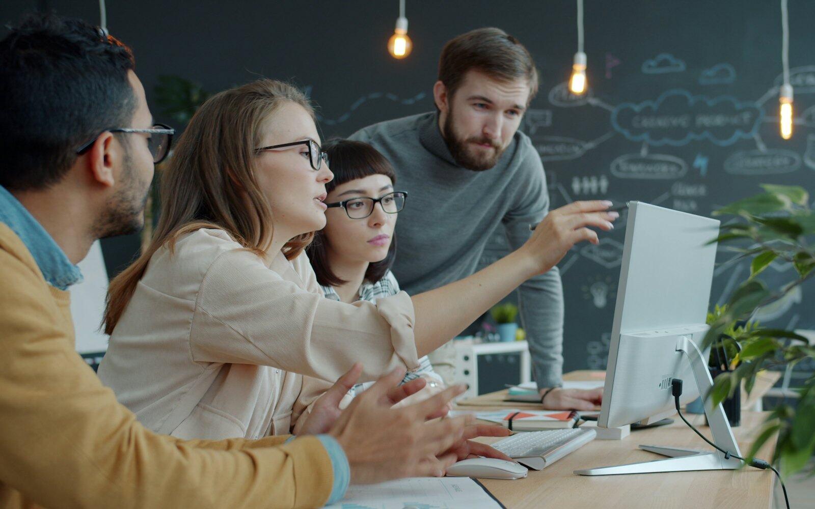 A team gathered around a laptop, one colleague pointing at the screen