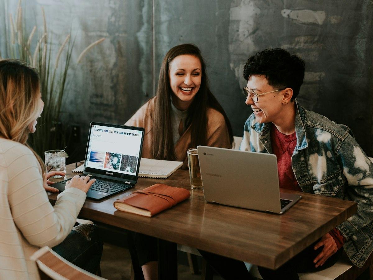 Young people laughing while working on laptops